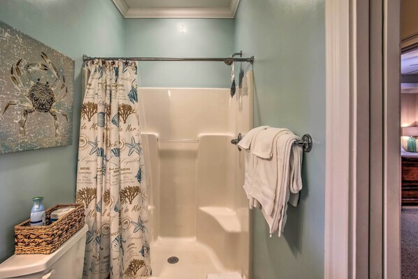 A bathroom with a shower, a toilet, a towel rack, and a decorative wall piece.