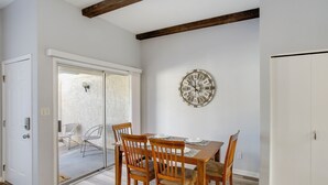 A dining area with a wooden table and chairs, a large wall clock, and a sliding glass door leading to an outdoor patio. - 4 Mi to Mill Ave: Family Retreat w/ Patio in Tempe (Tempe)