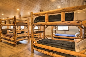 Bunk beds with wooden frames and black bedding, wooden floors, and a wooden ceiling with lights.