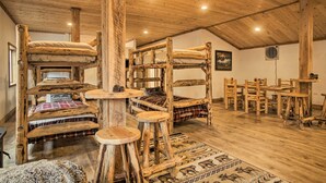 Una stanza rustica in legno con letti a castello, un tavolo da pranzo e sedie.
