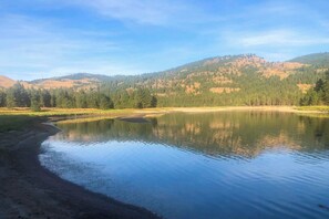 A calm lake with a forested hillside in the background.