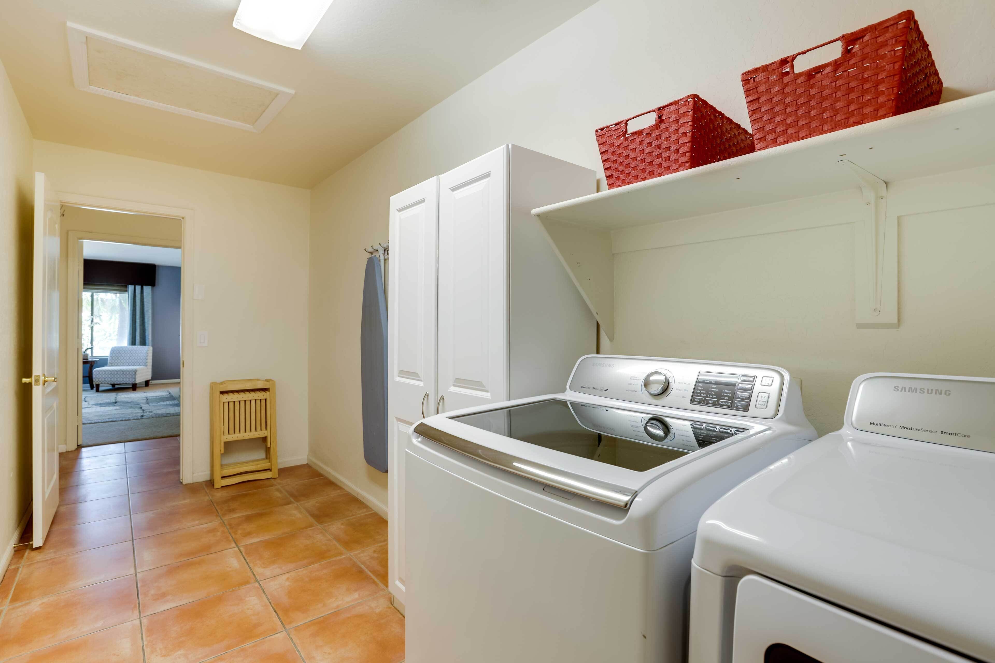 A laundry room with a washing machine, dryer, and shelves with baskets.