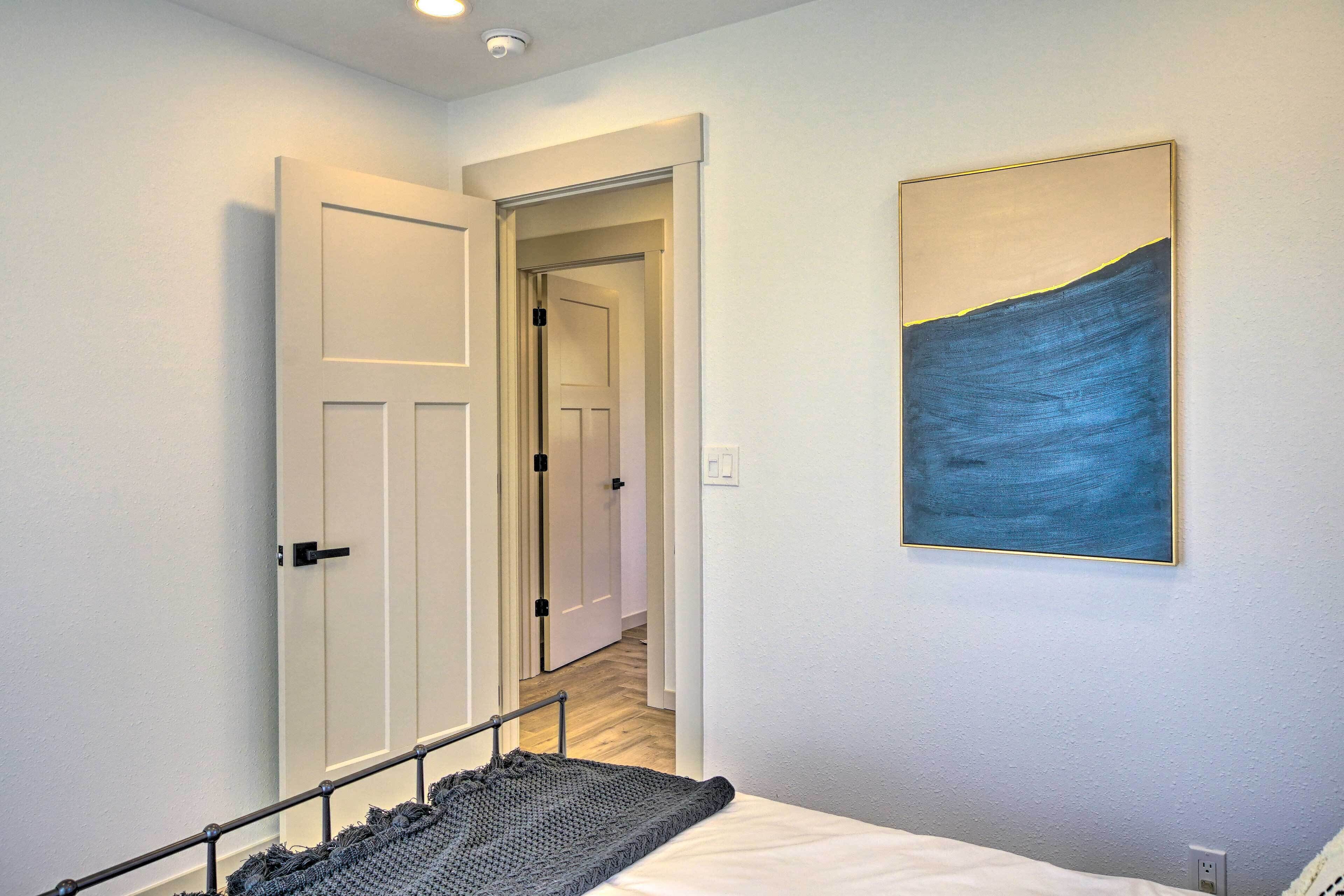 Un dormitorio con cama, un cuadro y una puerta que da a otra habitación.