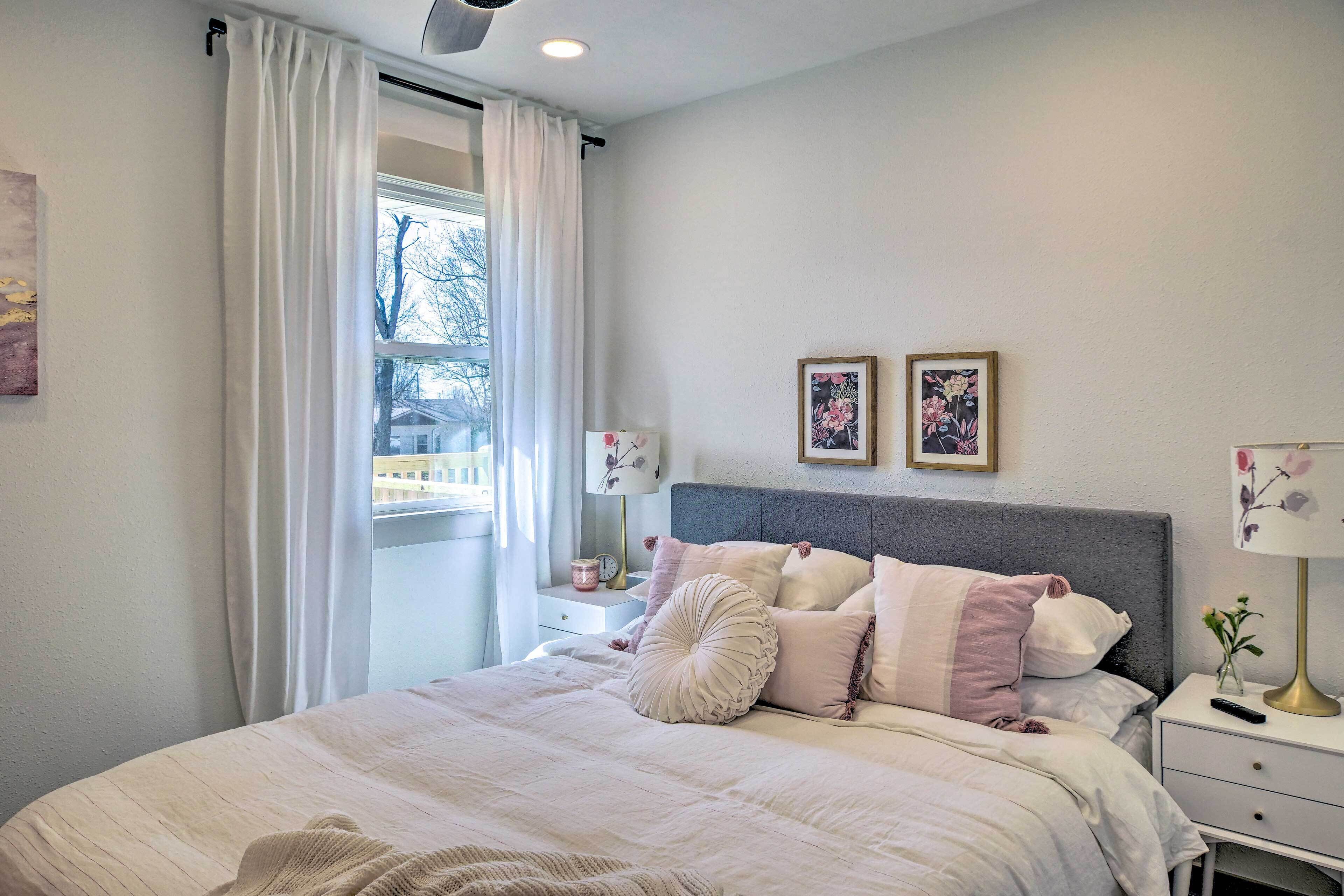 A bedroom with a bed, nightstands, a window with curtains, and two wall-mounted pictures.