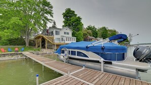 Ein Steg mit einem Boot, einem Haus und einer Reihe bunter Adirondack-Stühle.