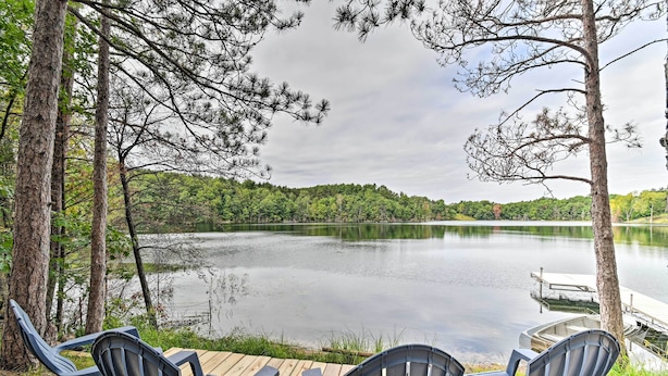 Een terras aan het meer met Adirondack-stoelen en een steiger die het water in loopt.