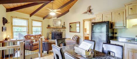 A spacious kitchen with wooden beams, a dining area with a marble table, and a cozy seating area with a fireplace.