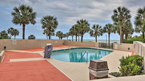 A pool area with palm trees, a barbecue grill, and a view of the ocean. - Myrtle Beach Ocean-view Condo: Walk to Beach! (Myrtle Beach)