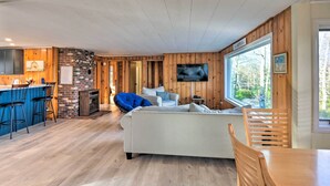 A cozy cabin interior with a kitchen area, a fireplace, a sofa, and a TV. - Updated Bristol Lakehouse w/ Kayaks & Beach Access (Bristol)