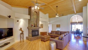 A spacious living room with a fireplace, wooden flooring, and a large sectional sofa. - Luxe Scottsdale Home w/ Horse Stables & Pool! (Scottsdale)
