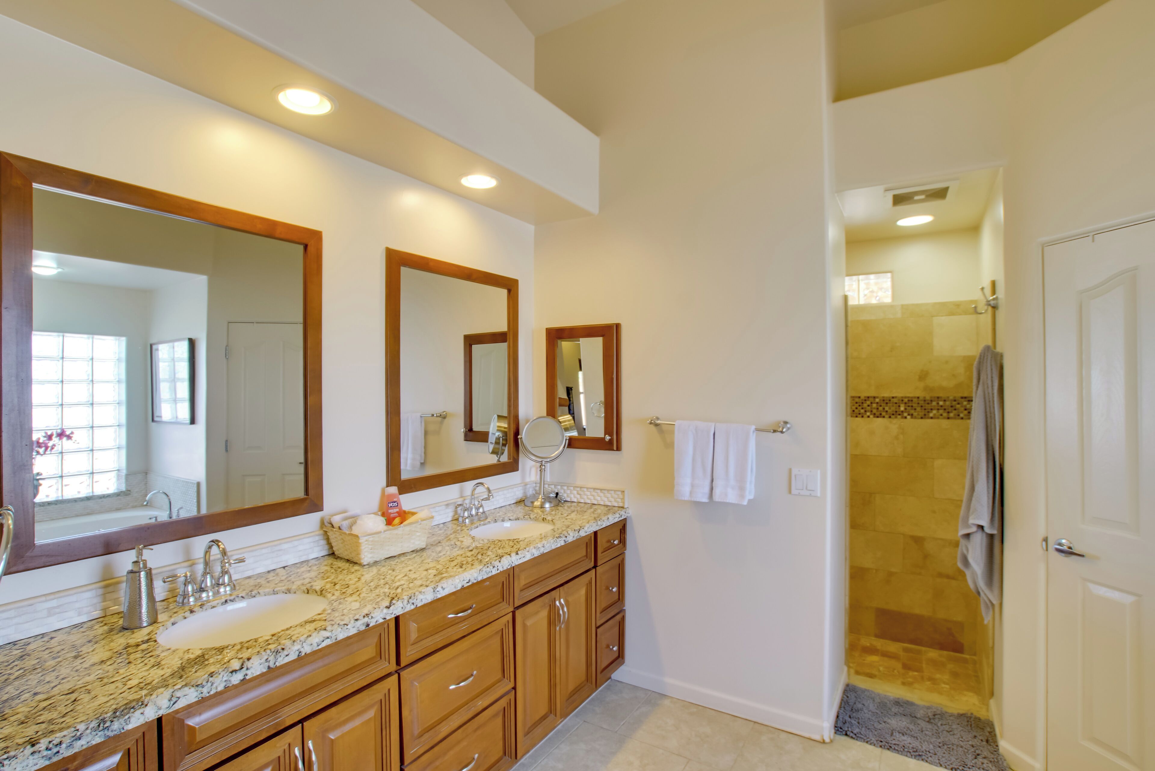 A bathroom with a large vanity, double sink, and a walk-in shower.