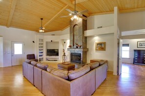 A spacious living room with a large L-shaped sectional sofa, a fireplace, and a ceiling fan.