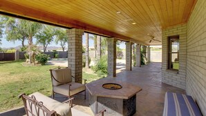 An outdoor patio area with a stone fire pit, seating, and a view of the surrounding landscape. - Luxe Scottsdale Home w/ Horse Stables & Pool! (Scottsdale)