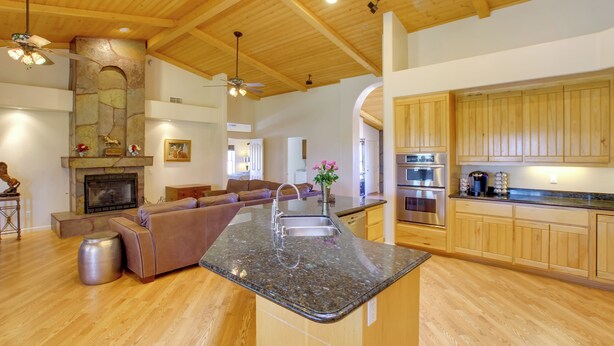 A spacious living area with a fireplace, a kitchen with wooden cabinets, and a dining area with a large island. - Luxe Scottsdale Home w/ Horse Stables & Pool! (Scottsdale)