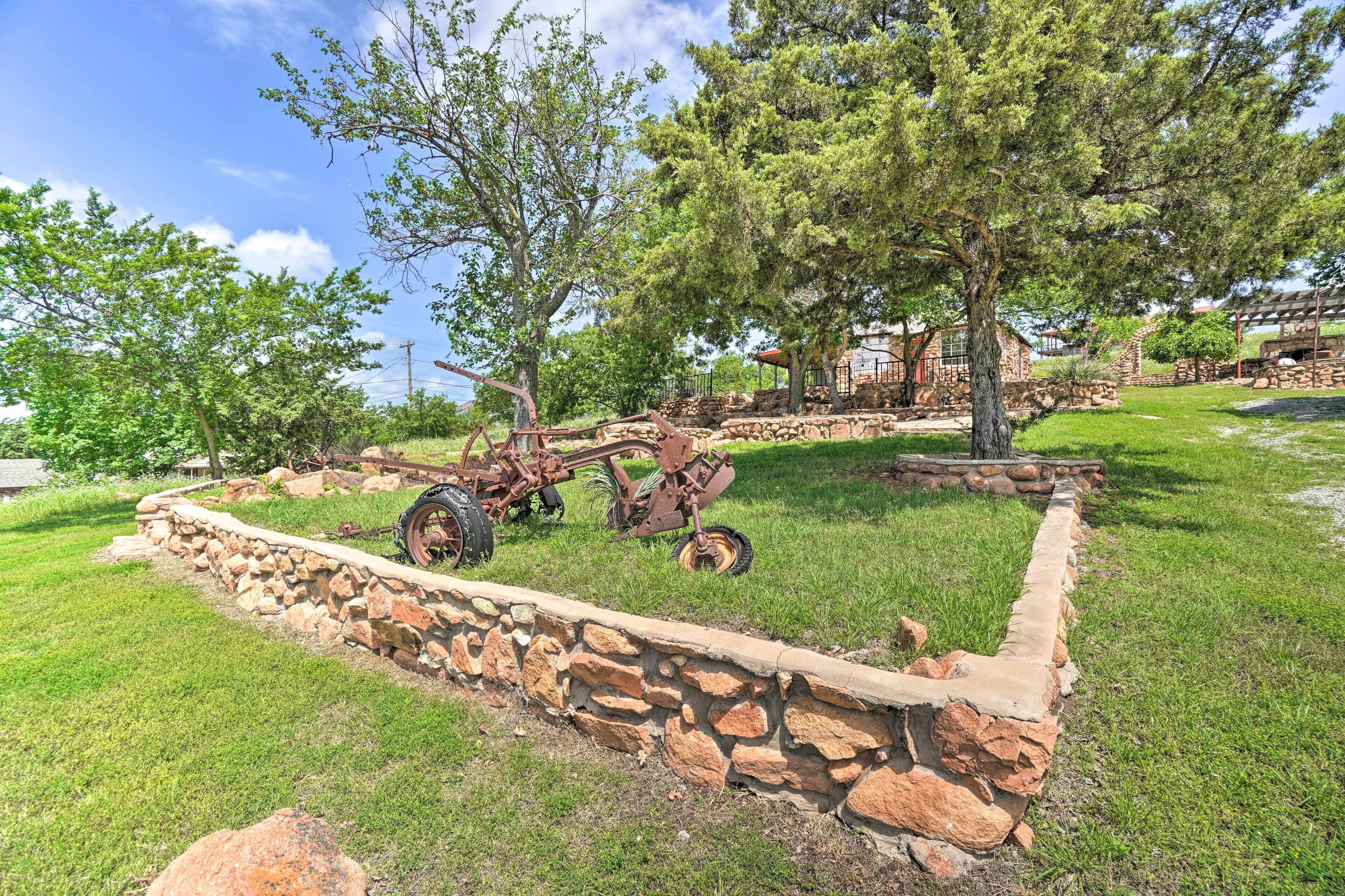 A rustic outdoor area with a stone wall, a tractor, and trees.