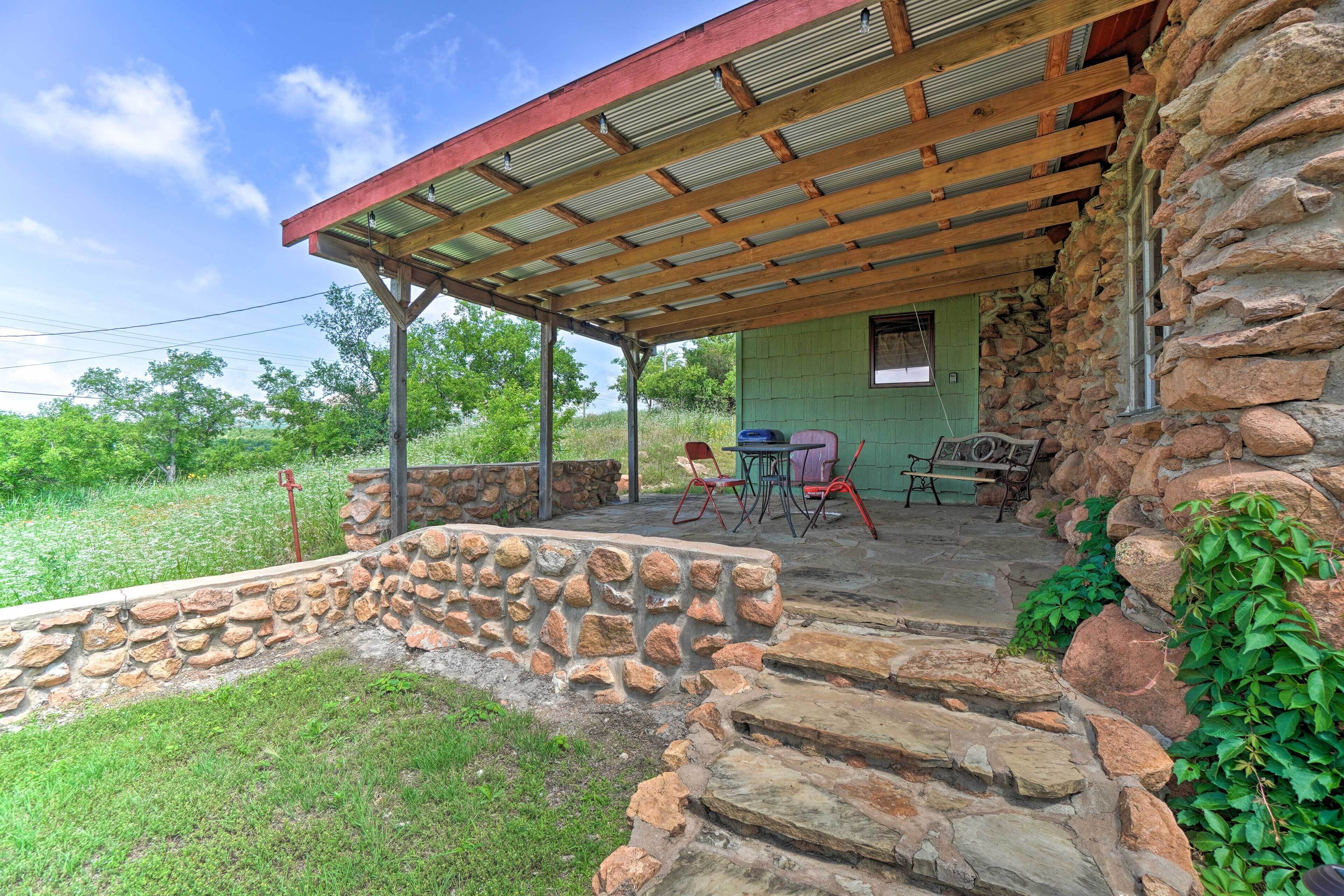 A stone building with a covered patio area, outdoor seating, and a stone wall.