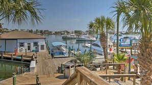 A marina with docked boats, a small building with an ice machine, and palm trees. - Ocean Views & Pool Access: Orange Beach Condo! (Orange Beach)