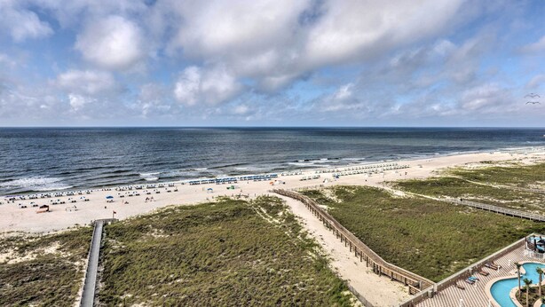 A beach resort with a long boardwalk, beach umbrellas, and a swimming pool. - Ocean Views & Pool Access: Orange Beach Condo! (Orange Beach)