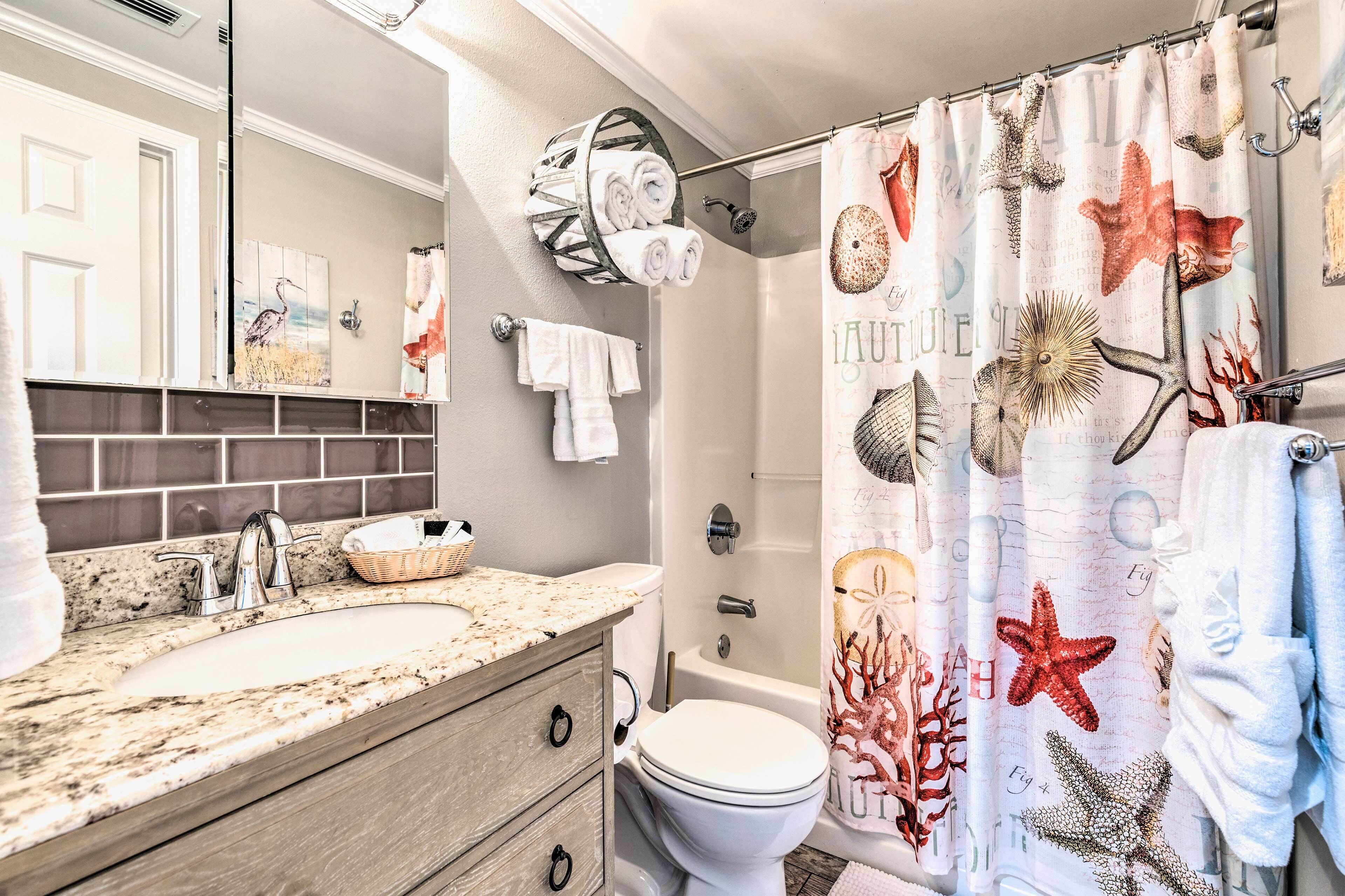 A bathroom with a double sink, a toilet, and a shower curtain with sea creature designs.