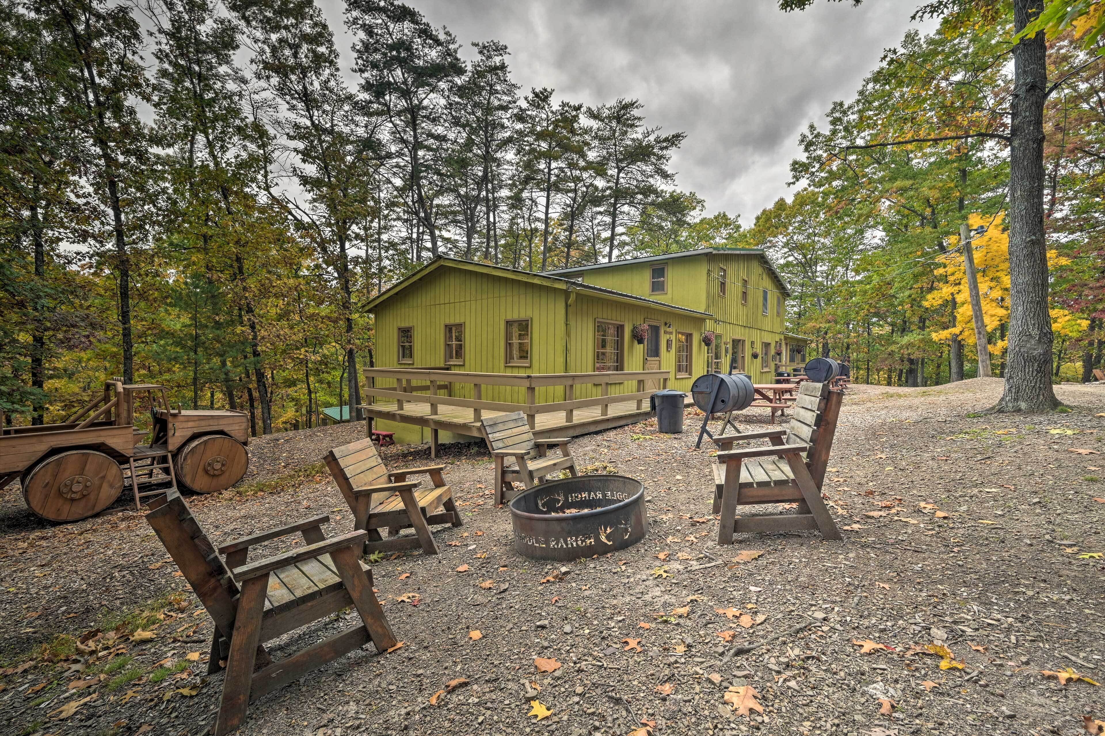 A rustic cabin with a deck, surrounded by trees and outdoor seating.