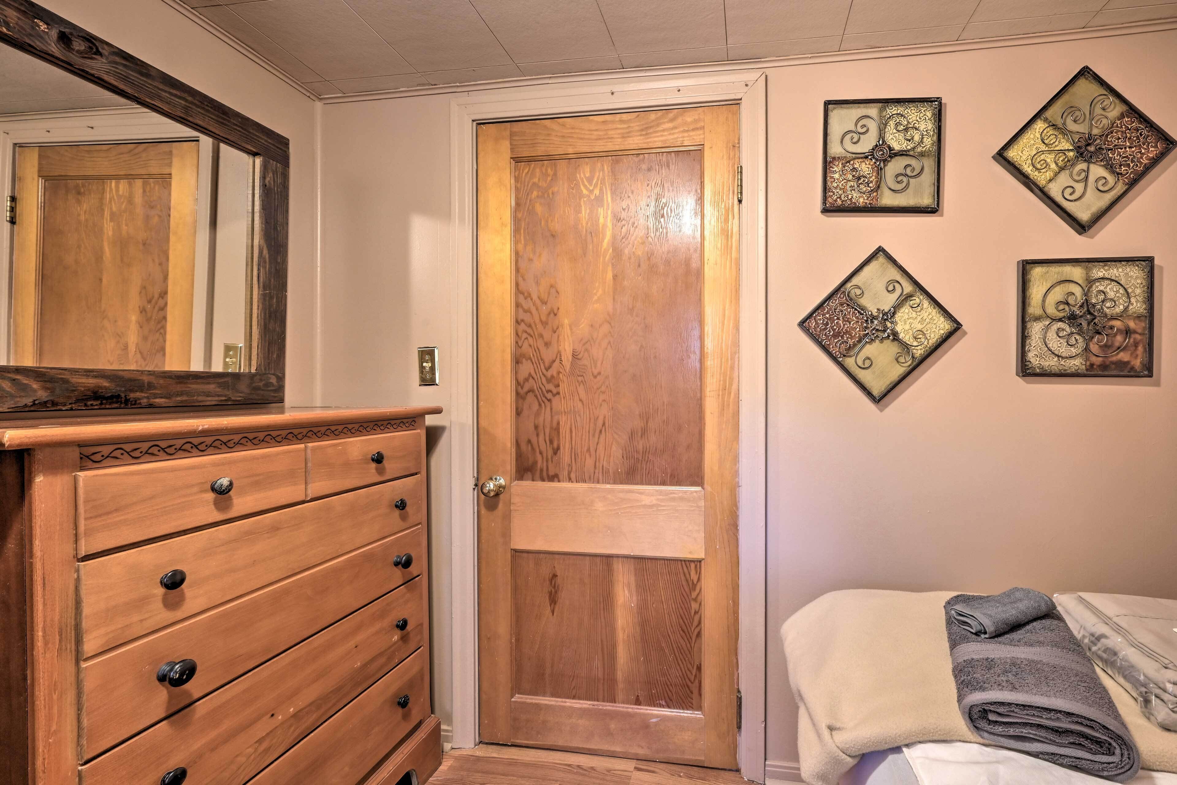 A room with a wooden dresser, a wooden door, and four wall-mounted decorative panels.