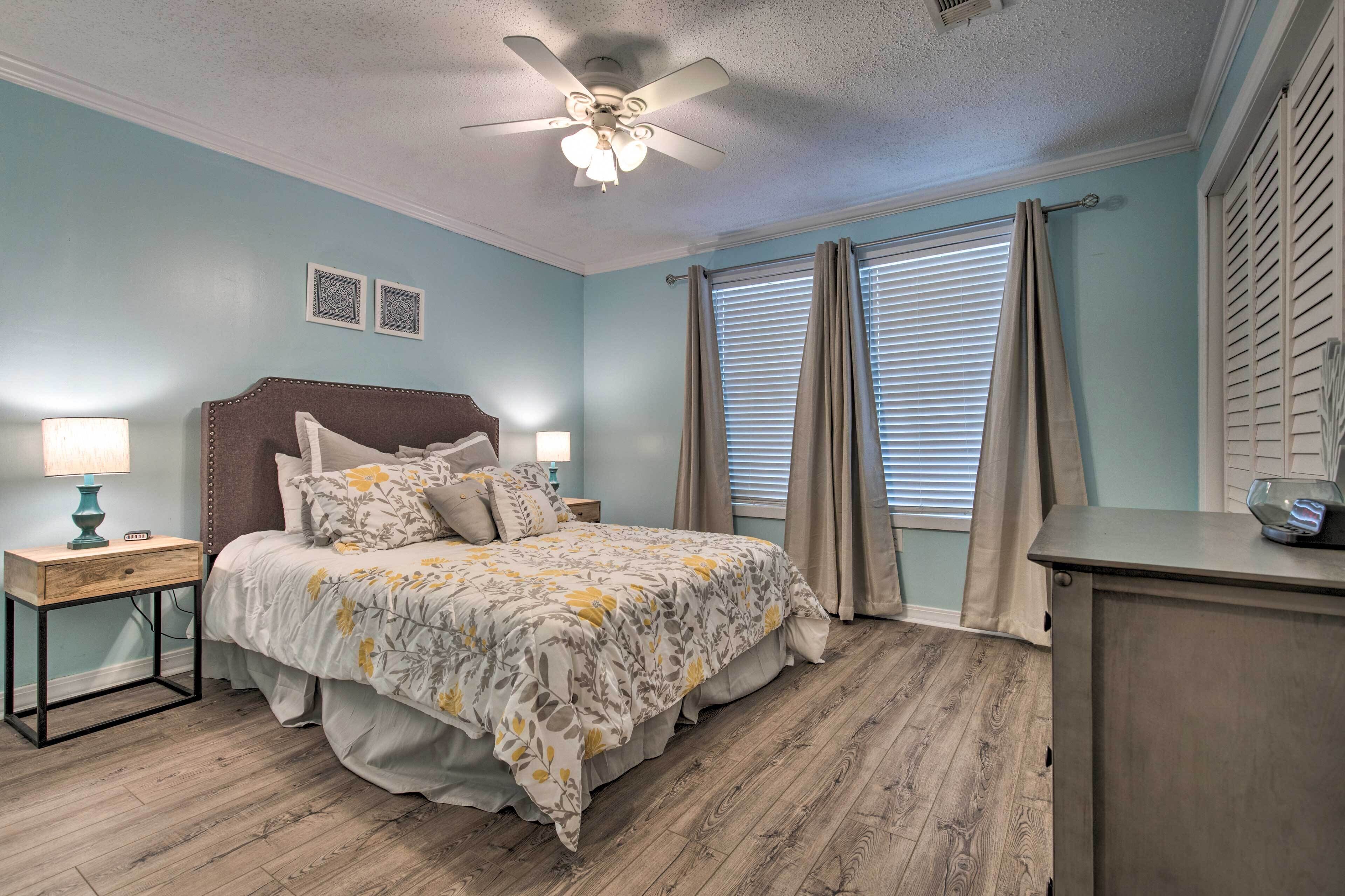 A bedroom with a bed, nightstands, a ceiling fan, and a window with curtains.