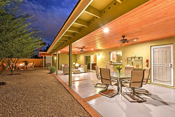 An outdoor patio area with a dining table and chairs, a ceiling fan, and a fire extinguisher.