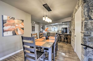 Une cuisine moderne avec un mur d’accent en pierre, un coin repas avec une table et des chaises en bois, et un luminaire suspendu.