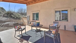 An outdoor patio with a covered seating area, two windows, and a view of the surrounding landscape. - Desert Gem w/ Patio + Grill, Near Oracle St. Park! (Oracle)
