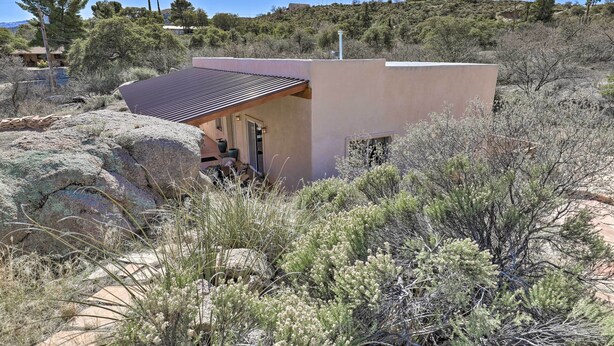 A modern house with a flat roof and a small porch, surrounded by dry vegetation and rocks. - Desert Gem w/ Patio + Grill, Near Oracle St. Park! (Oracle)