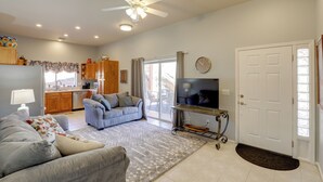 A living room with a sofa, a television, and a kitchen in the background. - Desert Gem w/ Patio + Grill, Near Oracle St. Park! (Oracle)