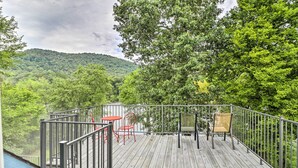 A wooden deck with metal railings, red chairs, and a beige chair. - Rubys Landing Cottage w/ Deck & White River Views (Melbourne)