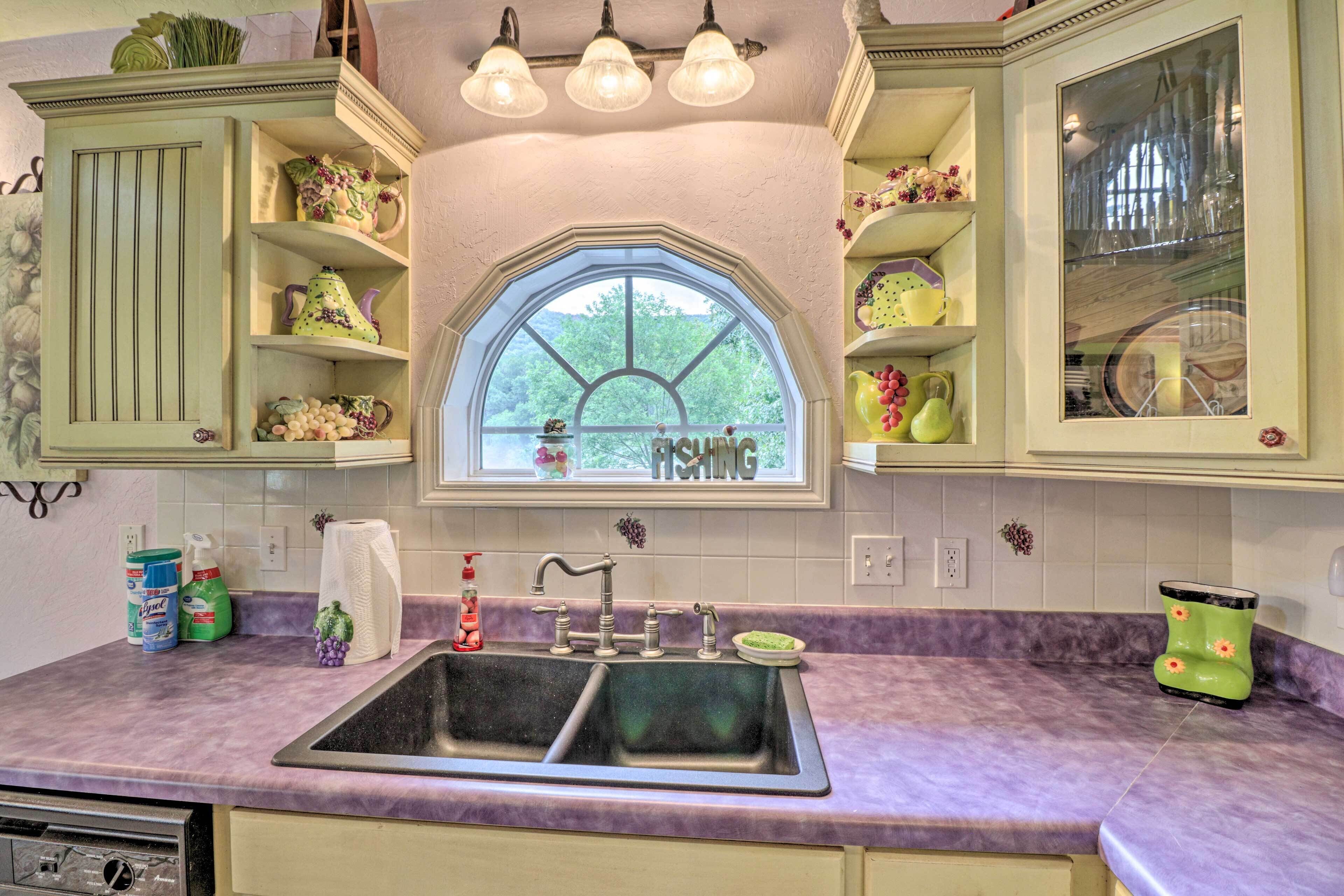 Una cocina con un ventanal grande, estantes empotrados y un lavabo.