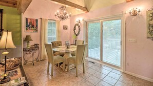 A dining area with a round table, four chairs, a chandelier, and a view through a glass door to an outdoor deck. - Rubys Landing Cottage w/ Deck & White River Views (Melbourne)