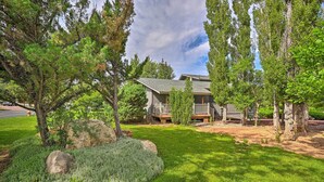 A two-story house with a covered porch, surrounded by mature trees and a well-maintained lawn. - Continental Country Club Gem w/ Covered Porch (Flagstaff)