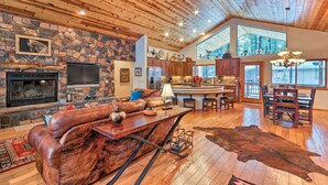 Un vaste espace de vie agrémenté d’une cheminée en pierre, d’un canapé en cuir et d’une grande table à manger en bois.