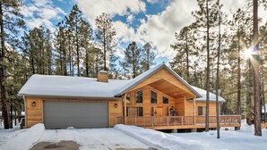 Une cabane en bois avec un garage, une véranda et un paysage enneigé.