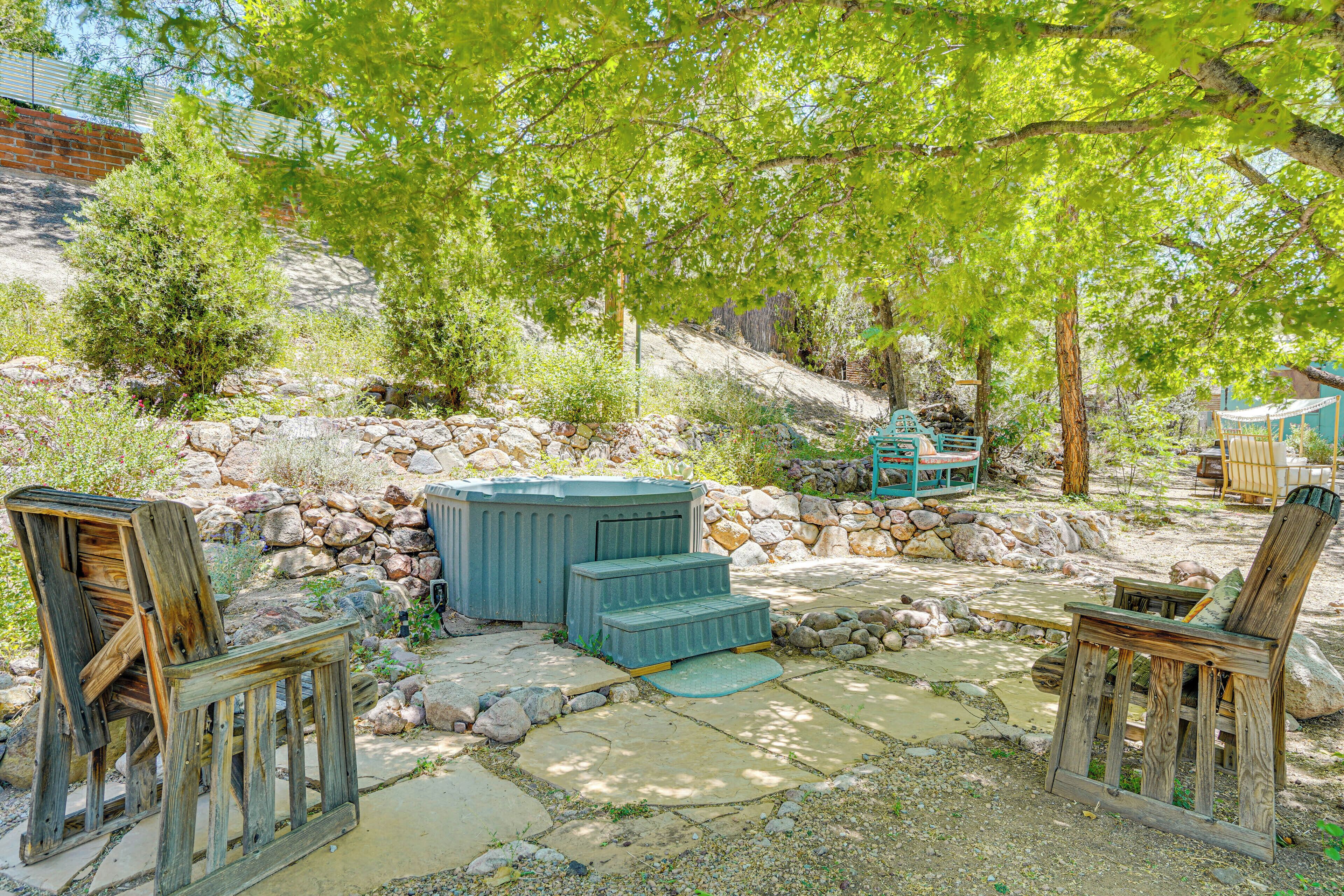 Un patio rústico al aire libre con escalones de piedra, muebles de madera y un muro de piedra.