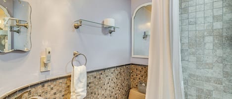 Un baño con lavamanos de mármol, inodoro y zona de ducha.