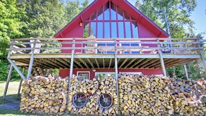 A red barn with a wooden deck and a pile of firewood in front. - East Burke House w/ Deck < 3 Mi to Kingdom Trails! (East Burke)
