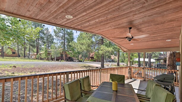 A covered outdoor patio with a table and chairs, a ceiling fan, and a view of a wooded area. - Coconino National Forest Home W/deck & Yard! (Munds Park)