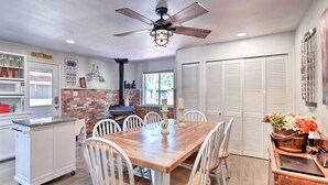 A dining area with a wooden table and chairs, a ceiling fan, and a brick wall. - Coconino National Forest Home W/deck & Yard! (Munds Park)