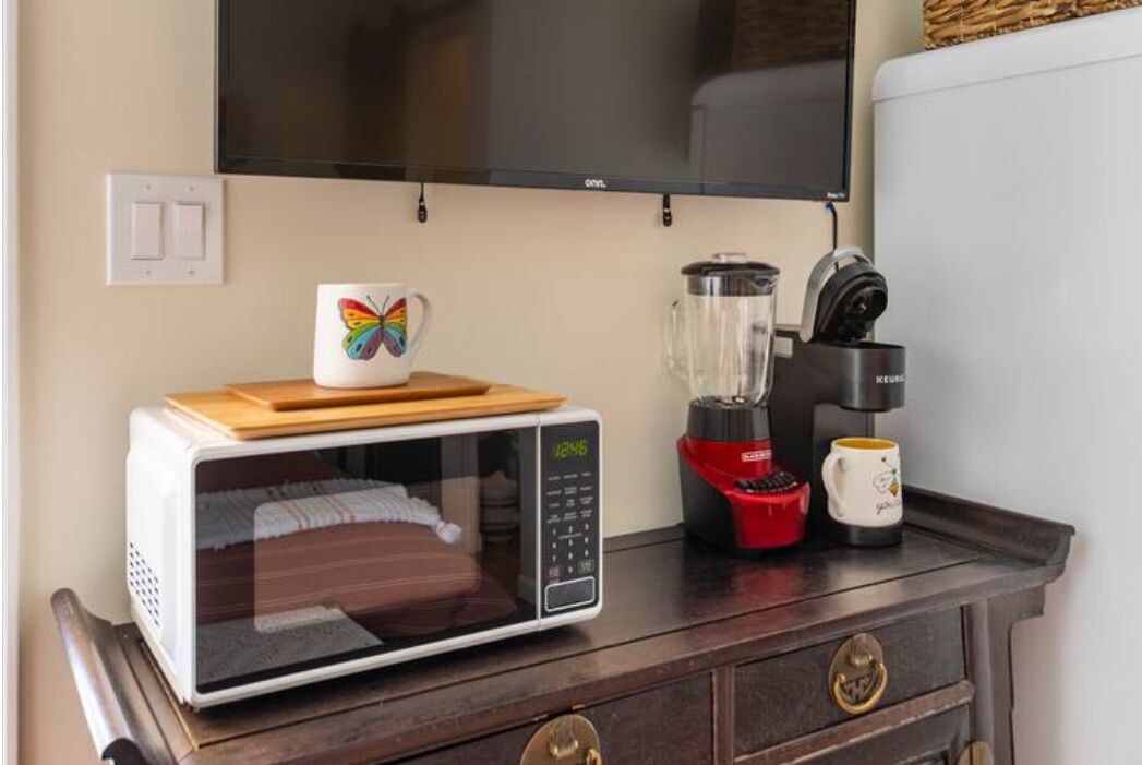 Una encimera de cocina con un microondas, una licuadora y una taza.
