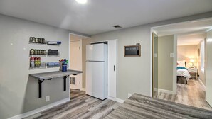 Une cuisine moderne dotée d’un réfrigérateur encastré, d’un petit plan de travail avec des récipients de rangement et d’un plancher en bois.