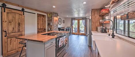 A spacious kitchen with a central island, wooden cabinets, and a large window providing natural light.