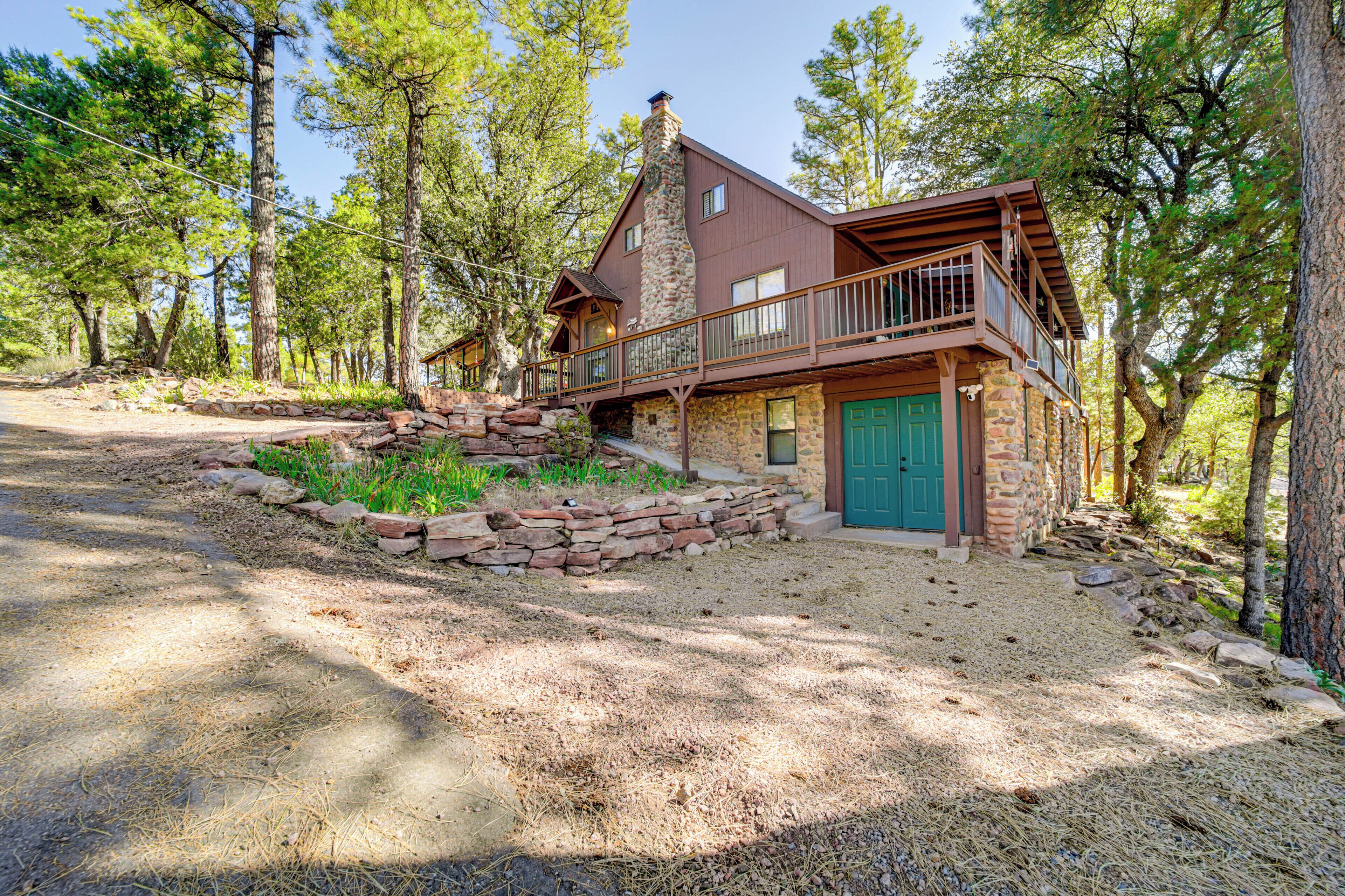 A rustic cabin with a stone foundation, a balcony, and a green door.