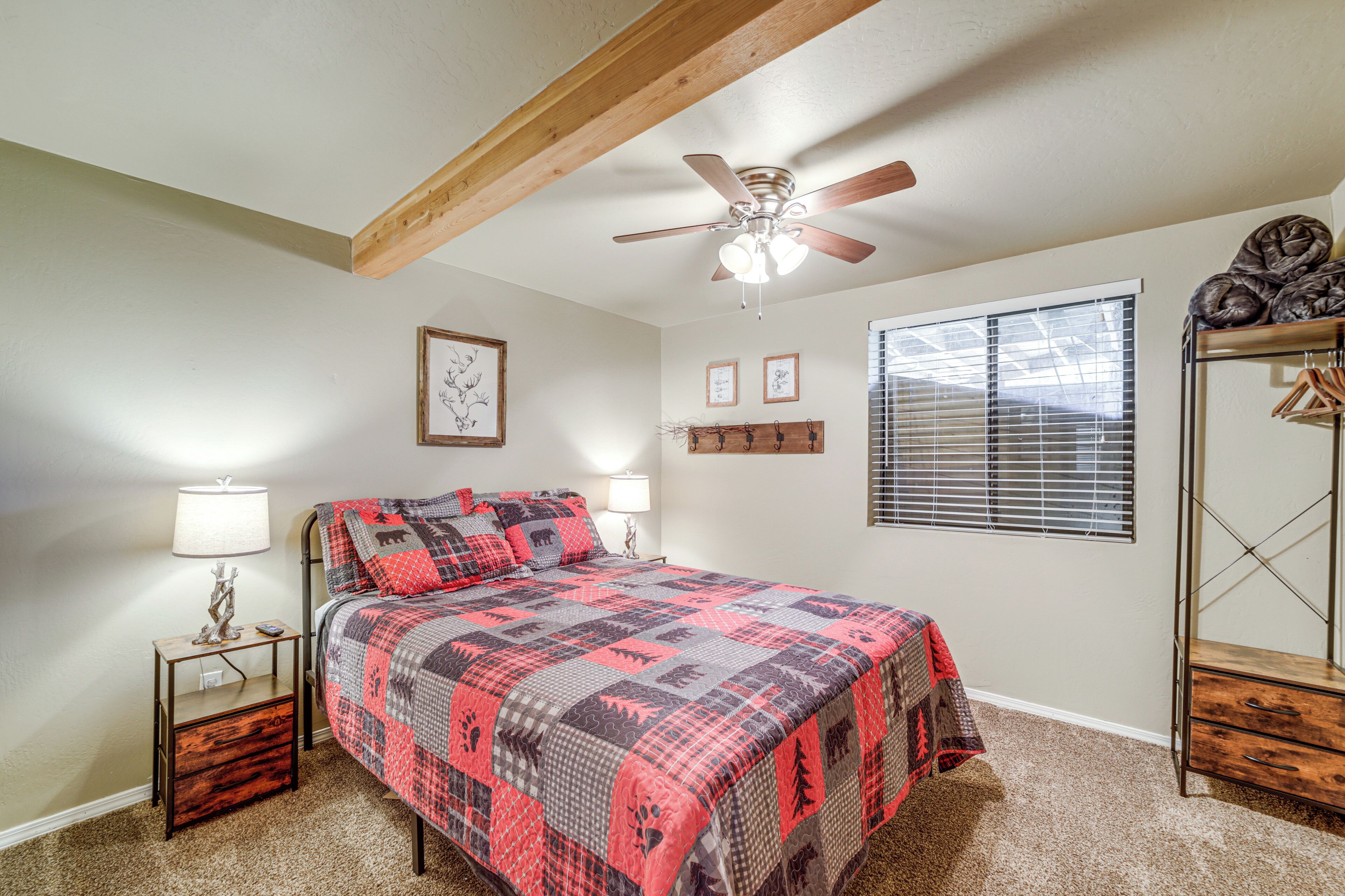 A bedroom with a bed, a ceiling fan, a window with blinds, a nightstand, and a dresser.