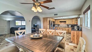 A spacious dining area with a wooden table and chairs, a ceiling fan, and a kitchen in the background. - 5 Mi to Marina: Lake Havasu City Home w/ Pool! (Lake Havasu City)