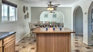 A kitchen with a central island, wooden cabinets, a dining table with chairs, and a ceiling fan. - 5 Mi to Marina: Lake Havasu City Home w/ Pool! (Lake Havasu City)