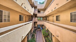 A multi-level atrium with a central walkway, balconies, and a view of the sky.